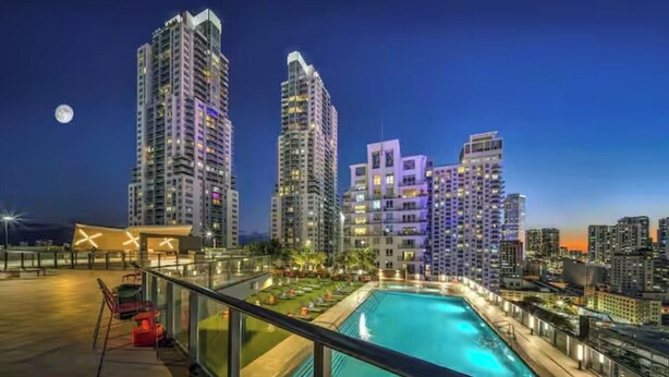 Uma área de piscina no terraço com vista para edifícios altos ao anoitecer.