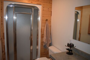 Un baño con cabina de ducha, inodoro, toallero y espejo.