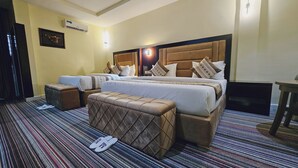 Habitació d'hotel amb un llit gran, dues taules de nit, una panxa i televisió, a sobre d'una catifes amb disseny.