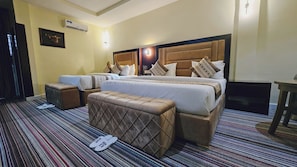 A hotel room with a large bed, two bedside tables, a bench, a TV, and a patterned carpet. - Villa Hilton Hotels and Apartments (Uyo)
