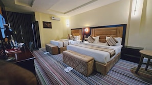 A hotel room with a large bed, two bedside tables, a desk, and a chair. - Villa Hilton Hotels and Apartments (Uyo)