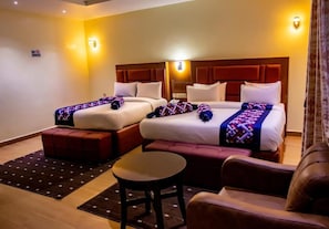 A hotel room with two beds, a sofa, a small table, and a 'No Smoking' sign on the wall. - Villa Hilton Hotels and Apartments (Uyo)