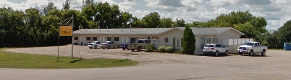 A motel with a parking lot, several cars parked, and a sign indicating the motel's name.
