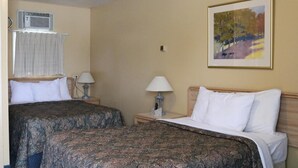 Ein Hotelzimmer mit zwei Betten, einem Bild an der Wand und einer Klimaanlage.