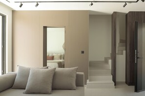 Una sala moderna con un sofá, una escalera y una puerta que da a otra habitación.
