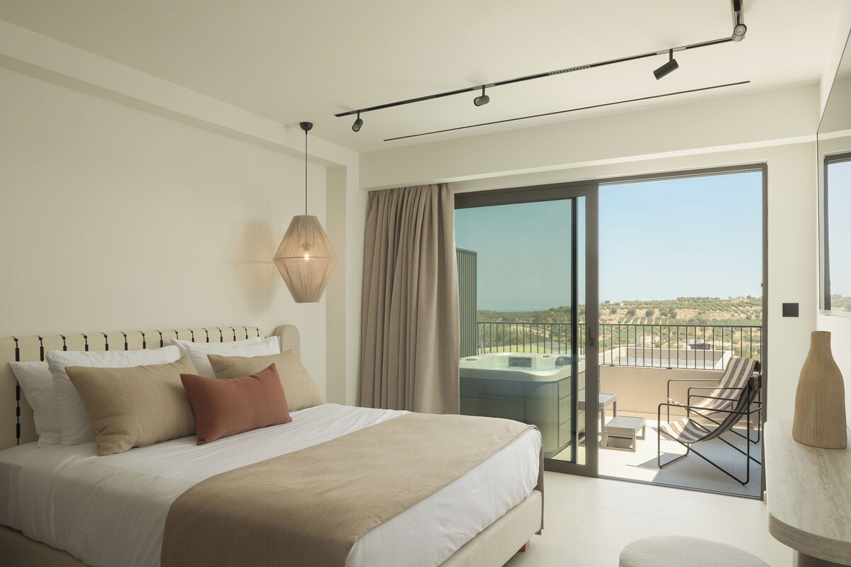 Habitación de hotel moderna con una cama grande, vista a un jacuzzi y un balcón con vistas al paisaje.