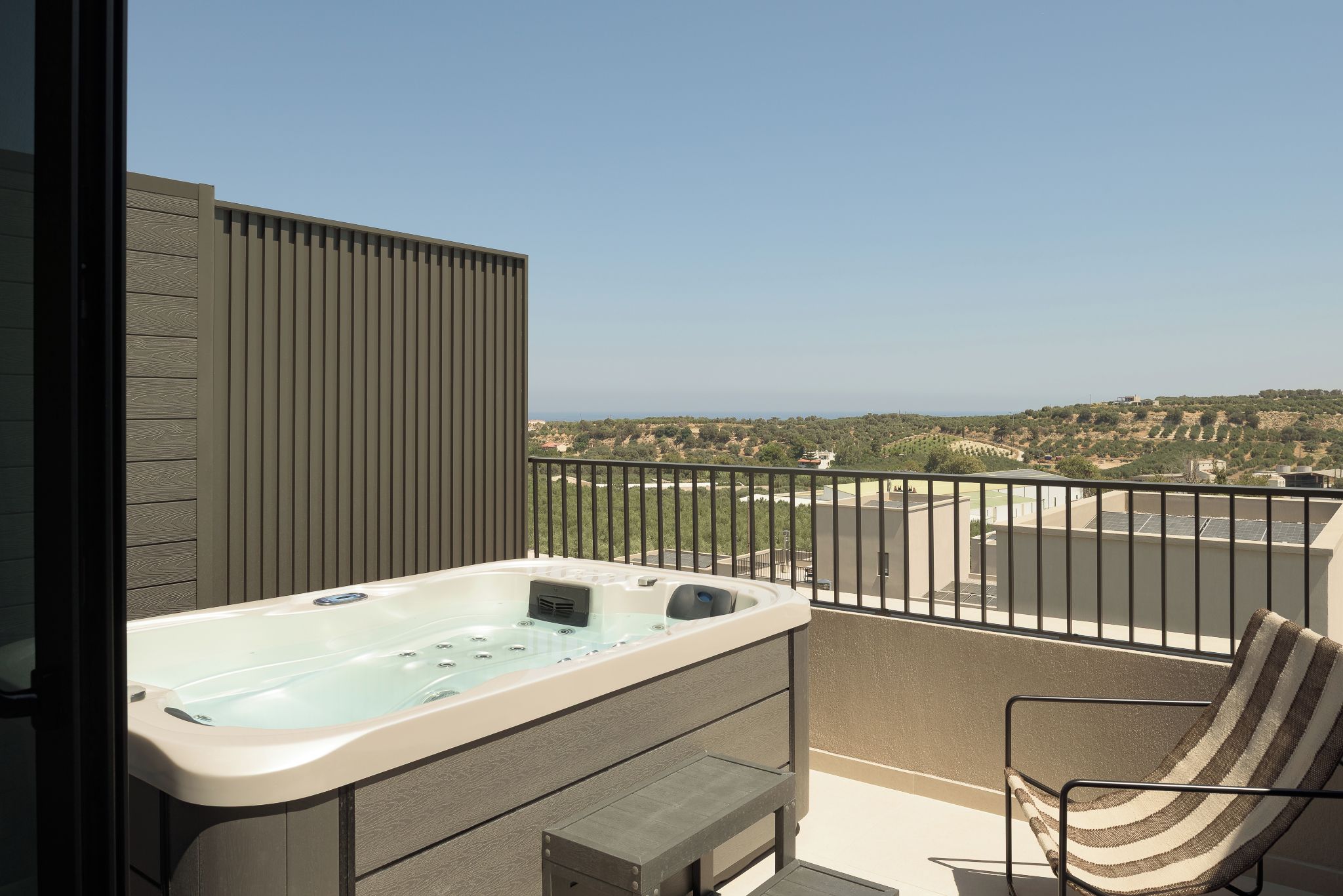 Un balcón con bañera de hidromasaje, una silla y vistas al paisaje.