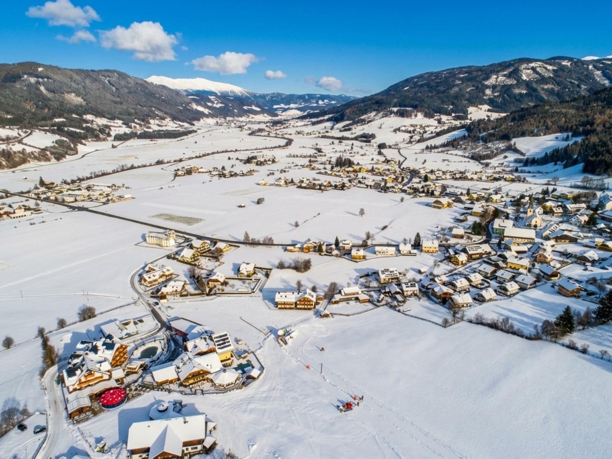 A snow-covered village with houses, a church, and a ski resort.