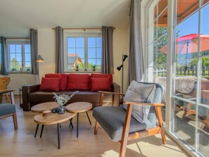Un salon comprenant un canapé, des fauteuils, une table basse et offrant une vue dégagée grâce à de grandes fenêtres.