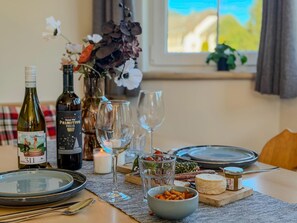 A dining table set with wine bottles, glasses, and a variety of food items. - Spacious Alpine holiday apartment on the slopes (Sankt Margarethen im Lungau)