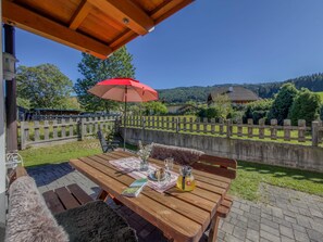 An outdoor wooden table with a red umbrella, a bench, and a picnic setup. - Spacious Alpine holiday apartment on the slopes (Sankt Margarethen im Lungau)