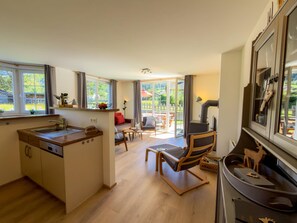Une cuisine moderne équipée d’un lave-vaisselle intégré, un coin repas avec une table et des chaises, et une grande porte-fenêtre coulissante donnant sur un patio extérieur.