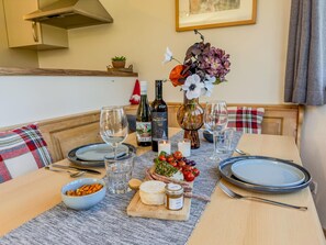 Une table à manger dressée avec des assiettes, des verres, une bouteille de vin, un vase rempli de fleurs et un petit bol de noix.