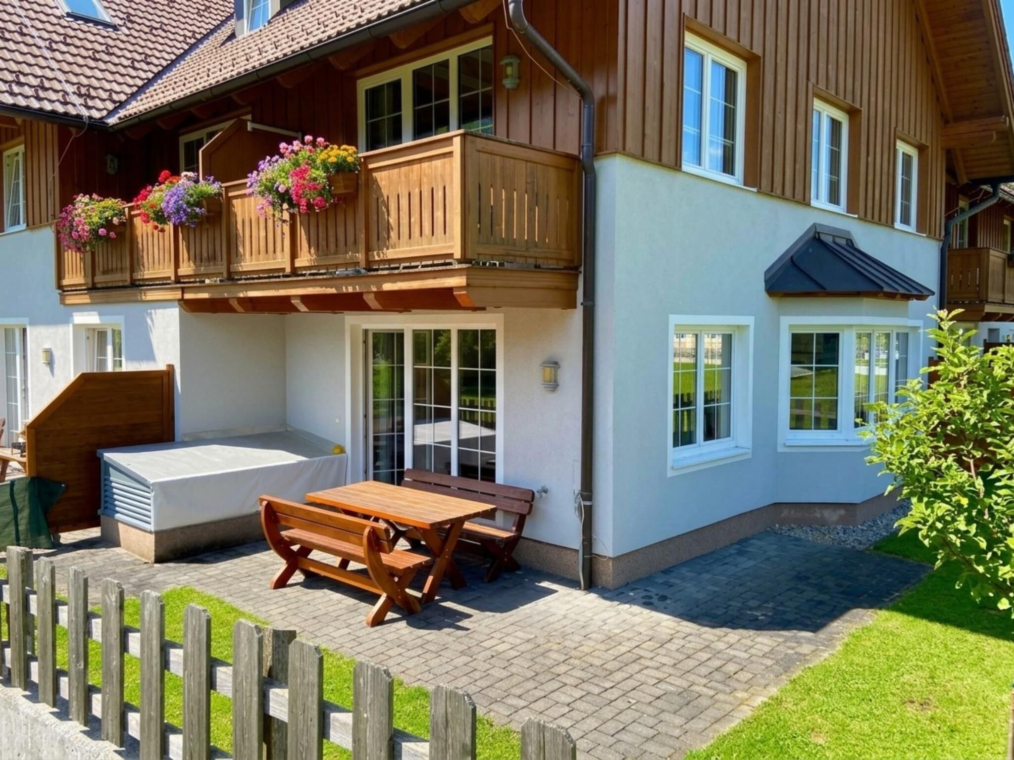 Un bâtiment à deux étages doté d’un balcon, d’un espace extérieur aménagé pour s’asseoir et d’une terrasse couverte.