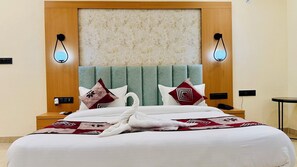A hotel room with a bed, a headboard, two wall-mounted lights, a nightstand, and a bedside table. - Kreston Heights Hotel Banquet & Restaurant (Bhopal)