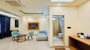 A hotel room with a seating area, a television mounted on the wall, and a bathroom visible through an open door. - Kreston Heights Hotel Banquet & Restaurant (Bhopal)