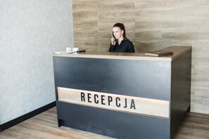 Un mostrador de recepción con un letrero que dice 'RECEPCJA' en un interior moderno con paneles de madera.