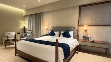 A hotel room with a large bed, two bedside tables, a chair, and a large window.