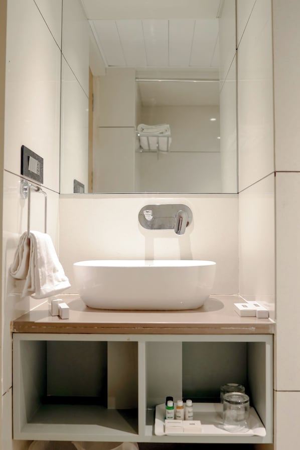A modern bathroom with a large white sink, a mirror, and a towel rack.