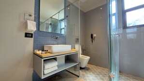 A modern bathroom with a glass shower enclosure, a white sink, and a toilet.