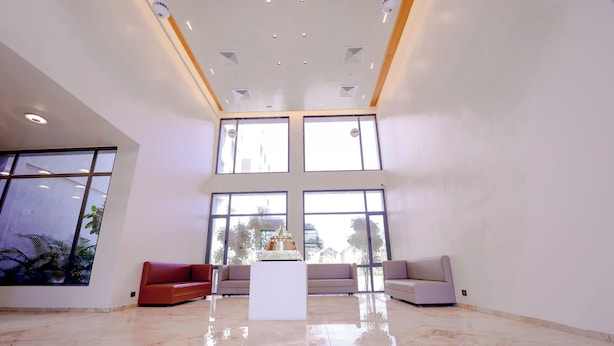 A spacious lobby with a high ceiling, large windows, and a polished marble floor.