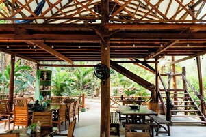 Una estructura de madera con techo, mesas, sillas y una escalera.