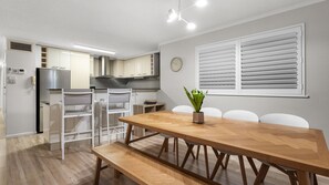 Eine moderne Küche mit weißen Schränken, einem Edelstahlkühlschrank und einem eingebauten Backofen.