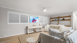 Ein Schlafzimmer mit einem Bett, einer weißen Kommode, einem kleinen runden Tisch und einem Deckenventilator.