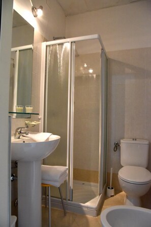 A bathroom with a glass-enclosed shower, a sink, a toilet, and a mirror. - Hotel Livio (Brescia)