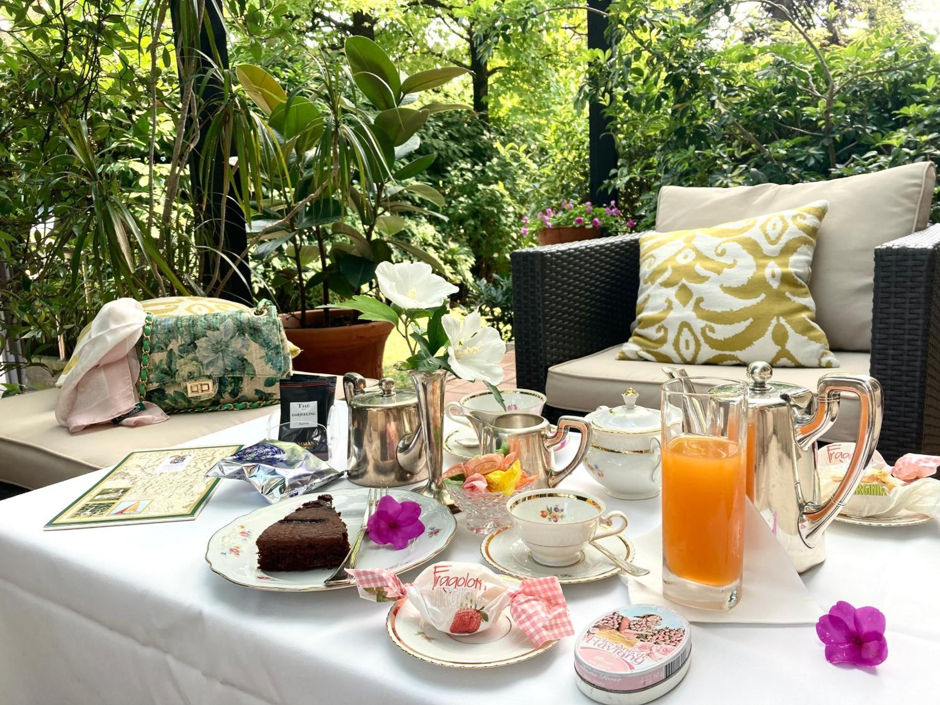 Mesa al aire libre lista para té y aperitivos, rodeada de abundante follaje.
