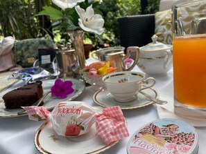 A table set with tea service, a glass pitcher, a teacup, a plate with a piece of cake, and a small container with a floral design. - Hotel Livio (Brescia)