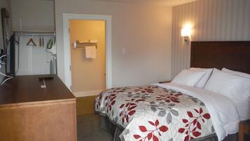 A hotel room with a bed, a desk, and a mirror.