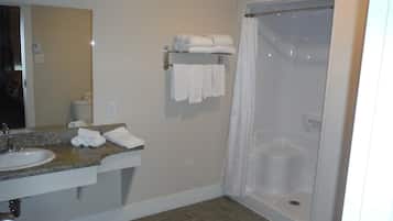 A bathroom with a sink, mirror, towel rack, and shower.