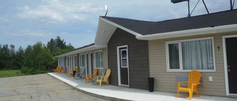A motel with a row of rooms, each with a door and windows.