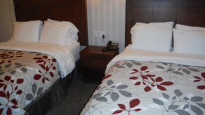 Ein Hotelzimmer mit zwei Betten, einem Nachttisch mit Telefon und einer Wandleuchte.