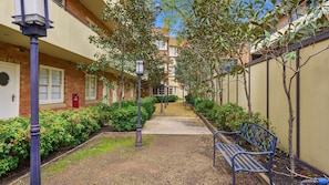 A pathway flanked by buildings with a bench and a fire hydrant. - The Brick House East Melbourne (East Melbourne)