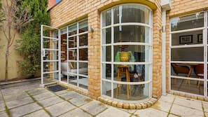 A corner building with large windows, a door, and a small outdoor seating area. - The Brick House East Melbourne (East Melbourne)