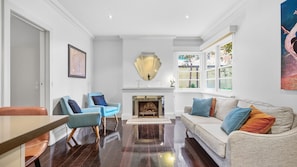 A living room with a fireplace, a sofa, two armchairs, and a dining table. - The Brick House East Melbourne (East Melbourne)