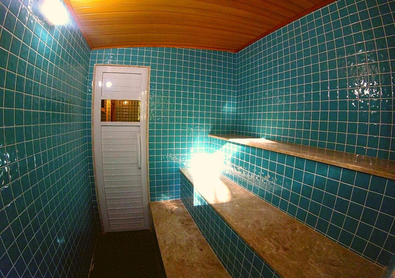 Casa de banho com azulejos azuis, uma porta branca e um banco.