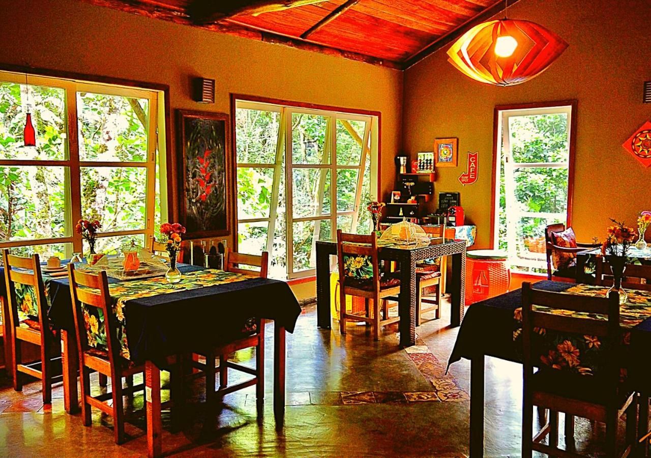 A dining area with multiple tables and chairs, large windows, and a ceiling fan.