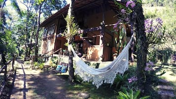 Uma casa de madeira rústica com uma rede na varanda.