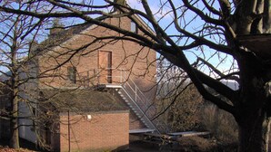 A brick building with a fire escape and a tree in the foreground. - Relaxing between the forest and Durbuy (Barvaux)