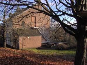 A brick building with a fire escape and a tree in the foreground. - Relaxing between the forest and Durbuy (Barvaux)