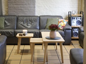A living room with a sofa, two tables, a candle, and a speaker system.