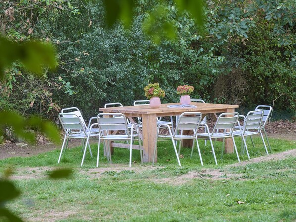 A wooden table with metal chairs, surrounded by greenery.