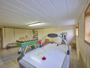 A room with a foosball table, a foosball table with a digital scoreboard, and a window.