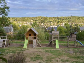 A playground with a wooden playhouse, slides, and climbing structures.