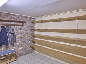 A laundry room with brick walls, metal shelving, and a bench.