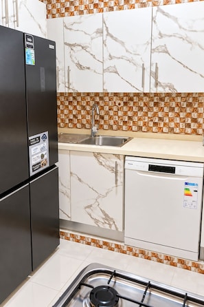 A kitchen with a refrigerator, sink, dishwasher, and gas stove.