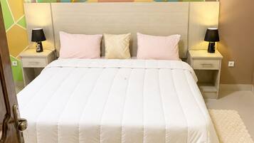 A bed with a white quilt, two bedside tables with lamps, and a wall with a geometric pattern.